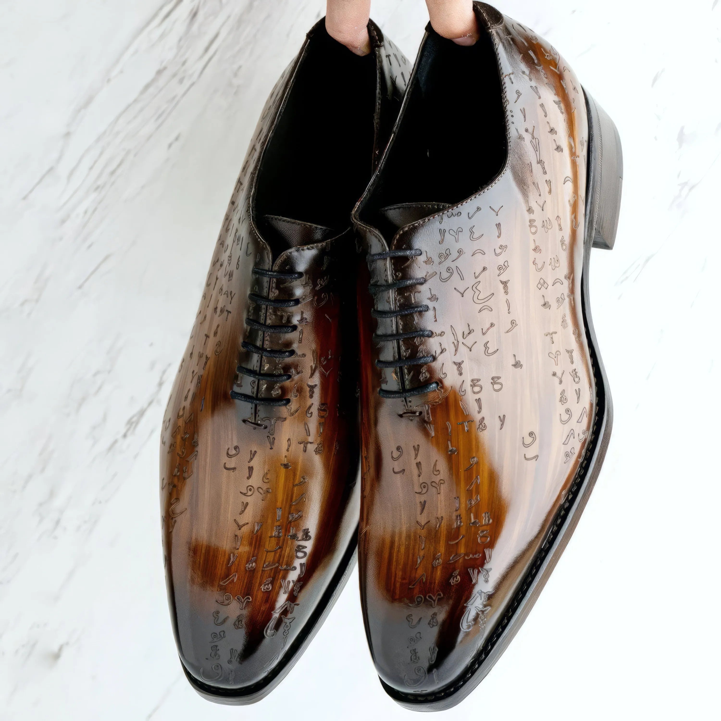 Polished brown-to-black oxblood leather dress shoes with intricate engraved script detailing along the sides.