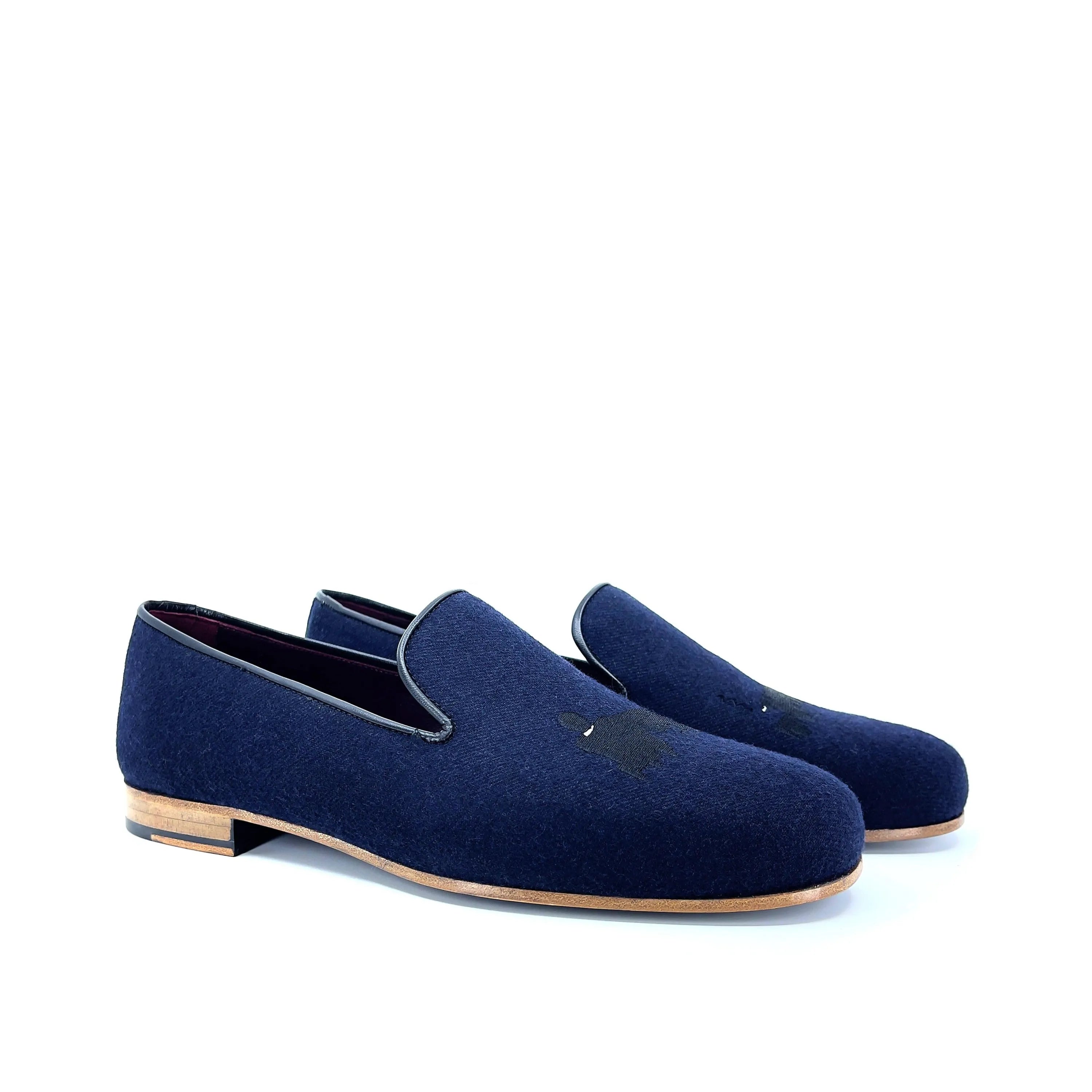 Navy blue suede loafers with a subtle black embroidered detail on the toe